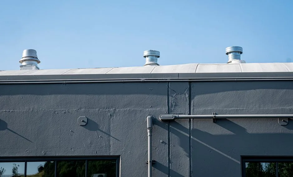 Low-angle view of industrial ventilation pipes and exhaust fans on a commercial rooftop