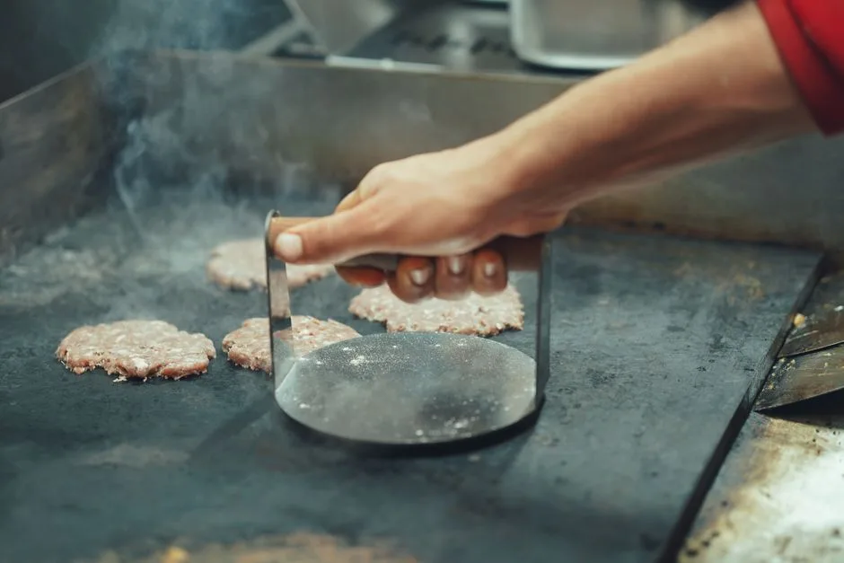 Chef cooking over commercial grill generating grease that flows to trap below